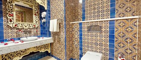 Un baño con lavamanos, espejo, inodoro y azulejos decorativos.