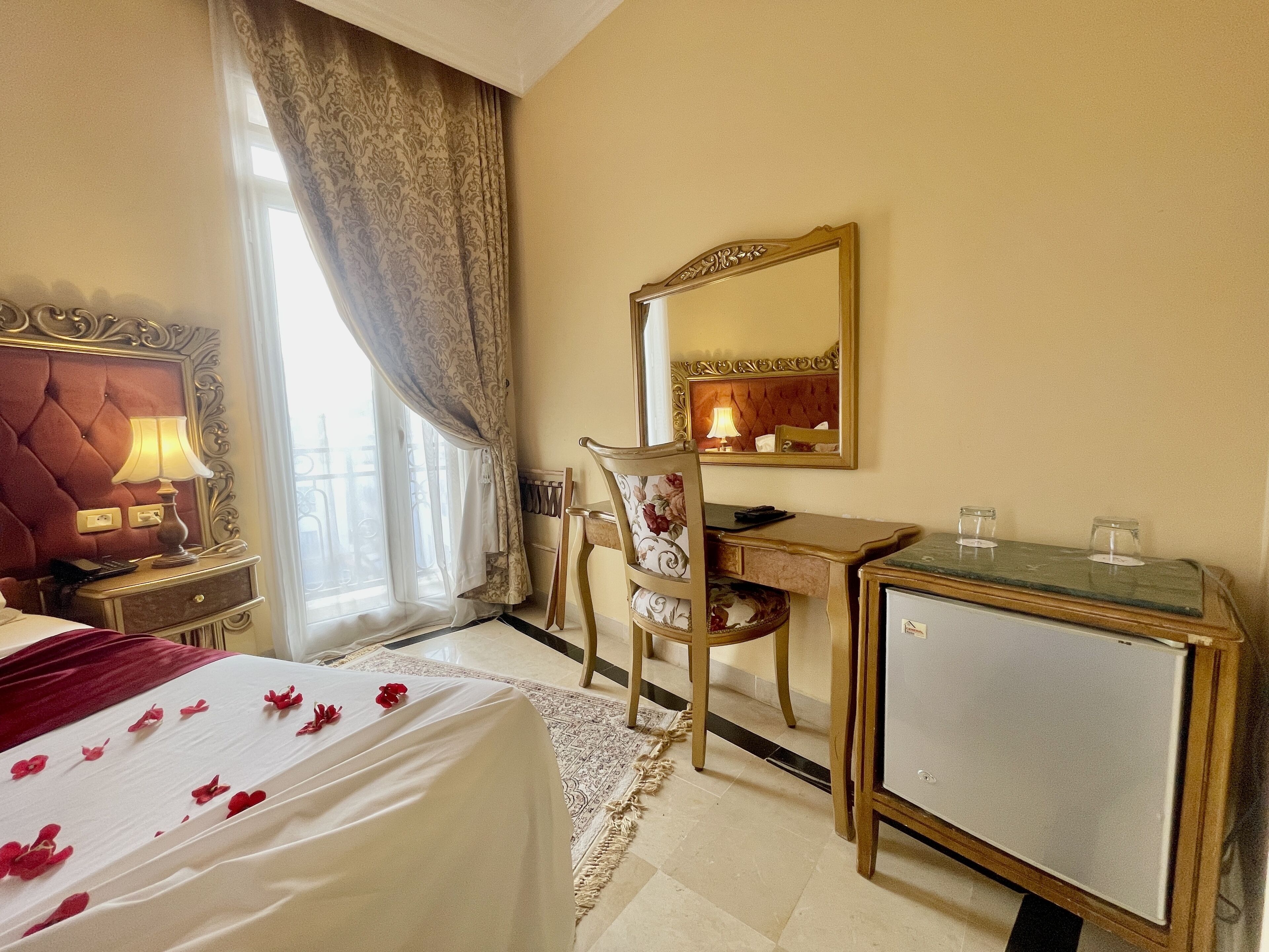 A hotel room with a bed, a desk, a chair, a dresser, and a mirror.