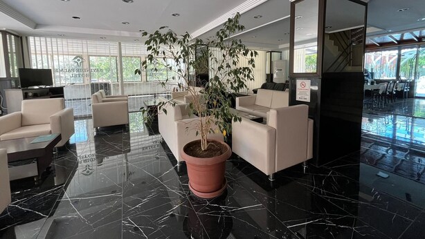 A modern lobby with a large potted plant, seating area, and a large mirror. - Bayindir Palme (Antalya)