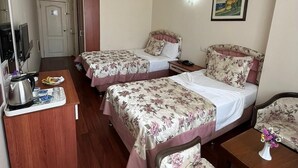 A hotel room with two beds, a desk with a kettle, a chair, and a small table with a vase. - Bayindir Palme (Antalya)