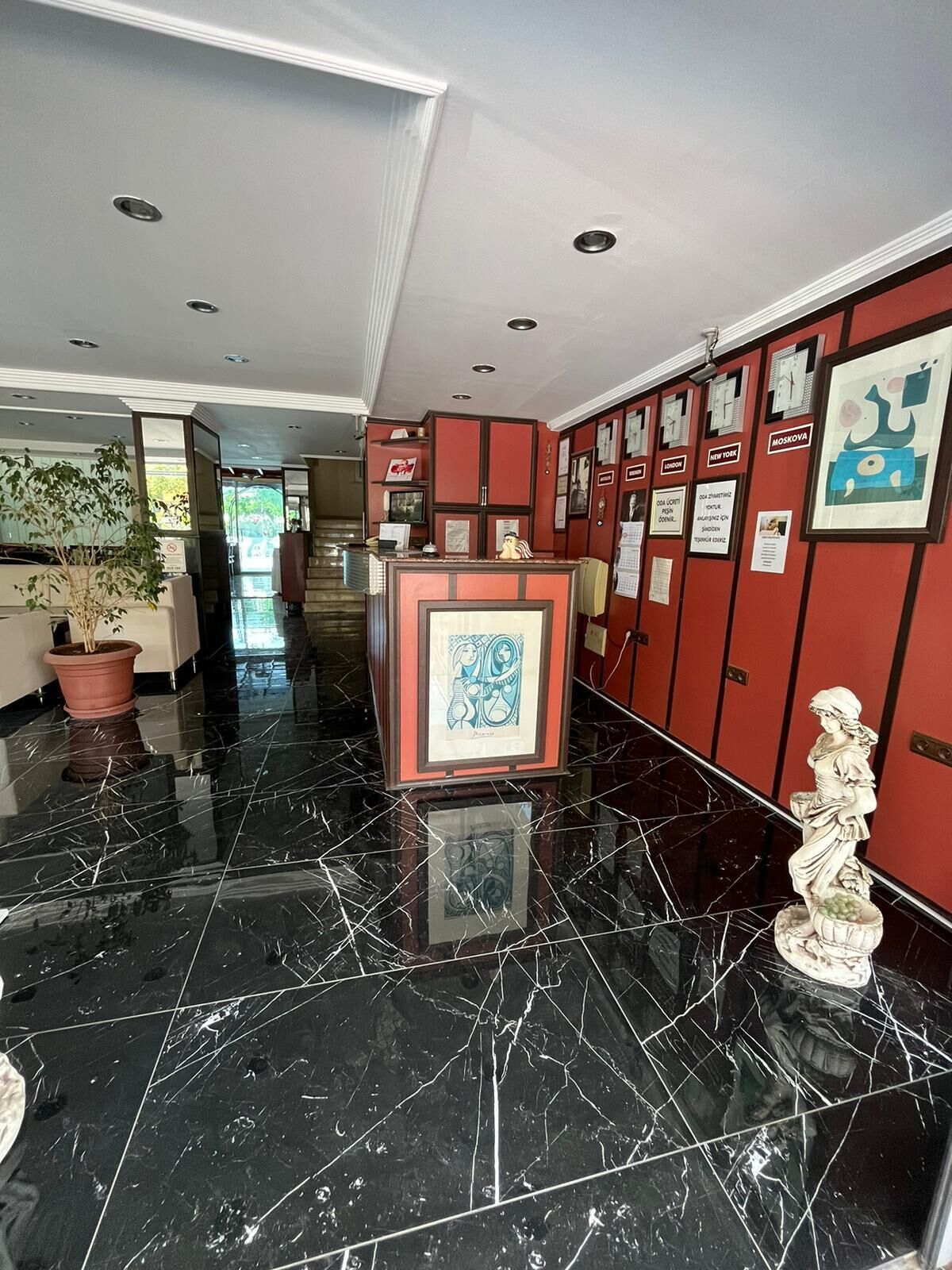 A hotel lobby with a marble floor, a reception desk, and red lockers with city names on them.