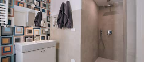 A modern bathroom with a white sink, a mirror, and a shower area.