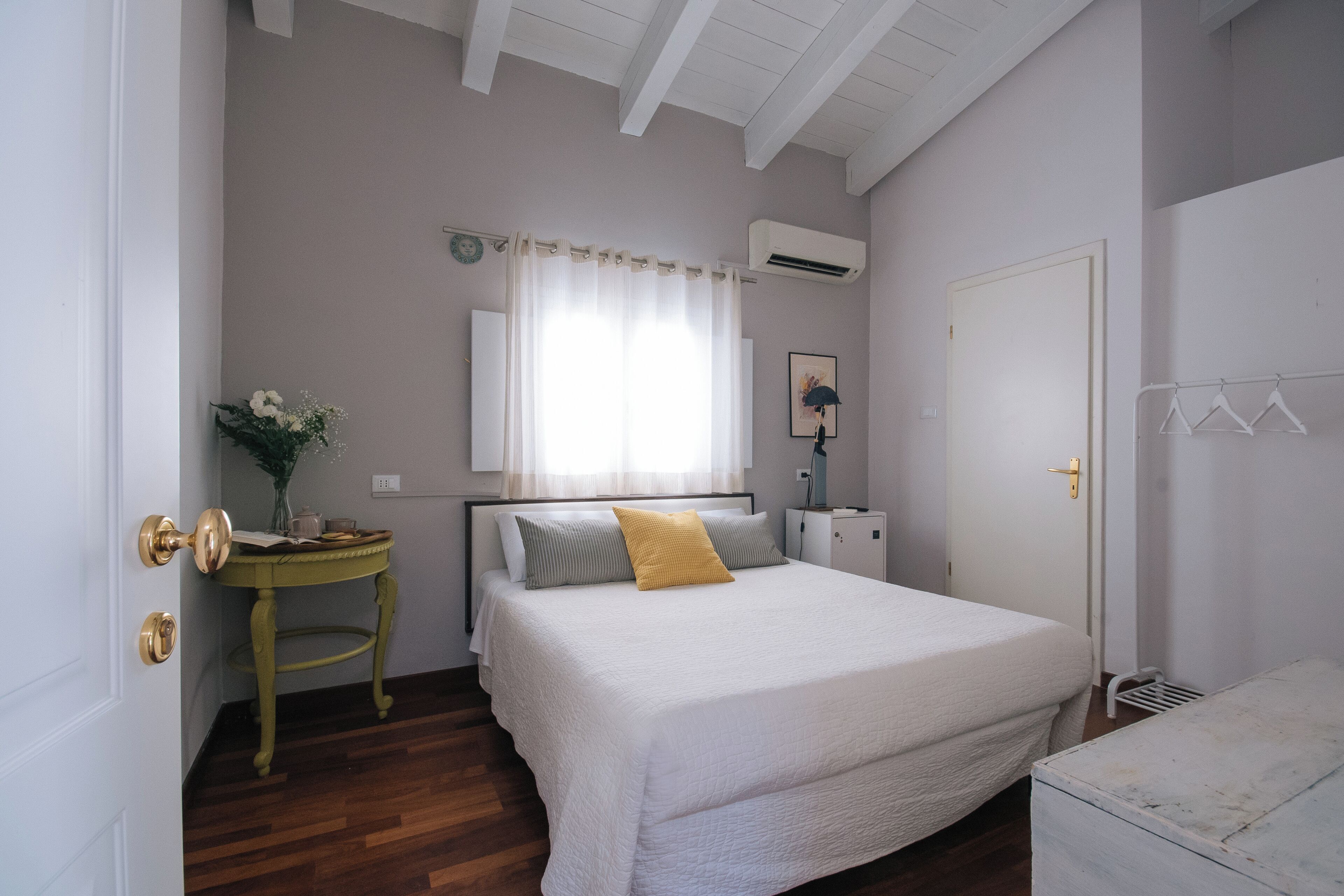 A bedroom with a bed, bedside table, and a mirror.