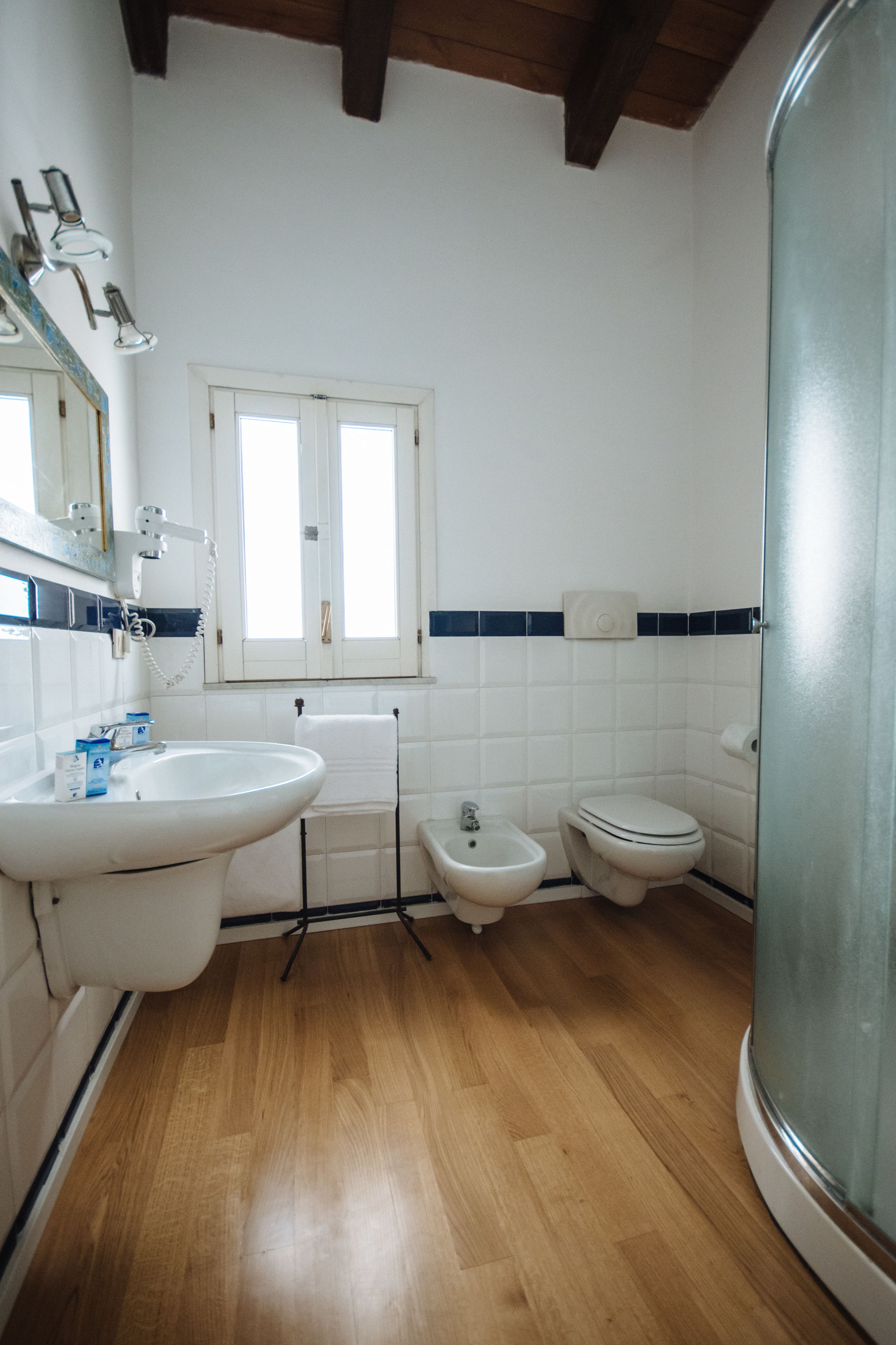 A bathroom with a sink, bidet, toilet, and a window.