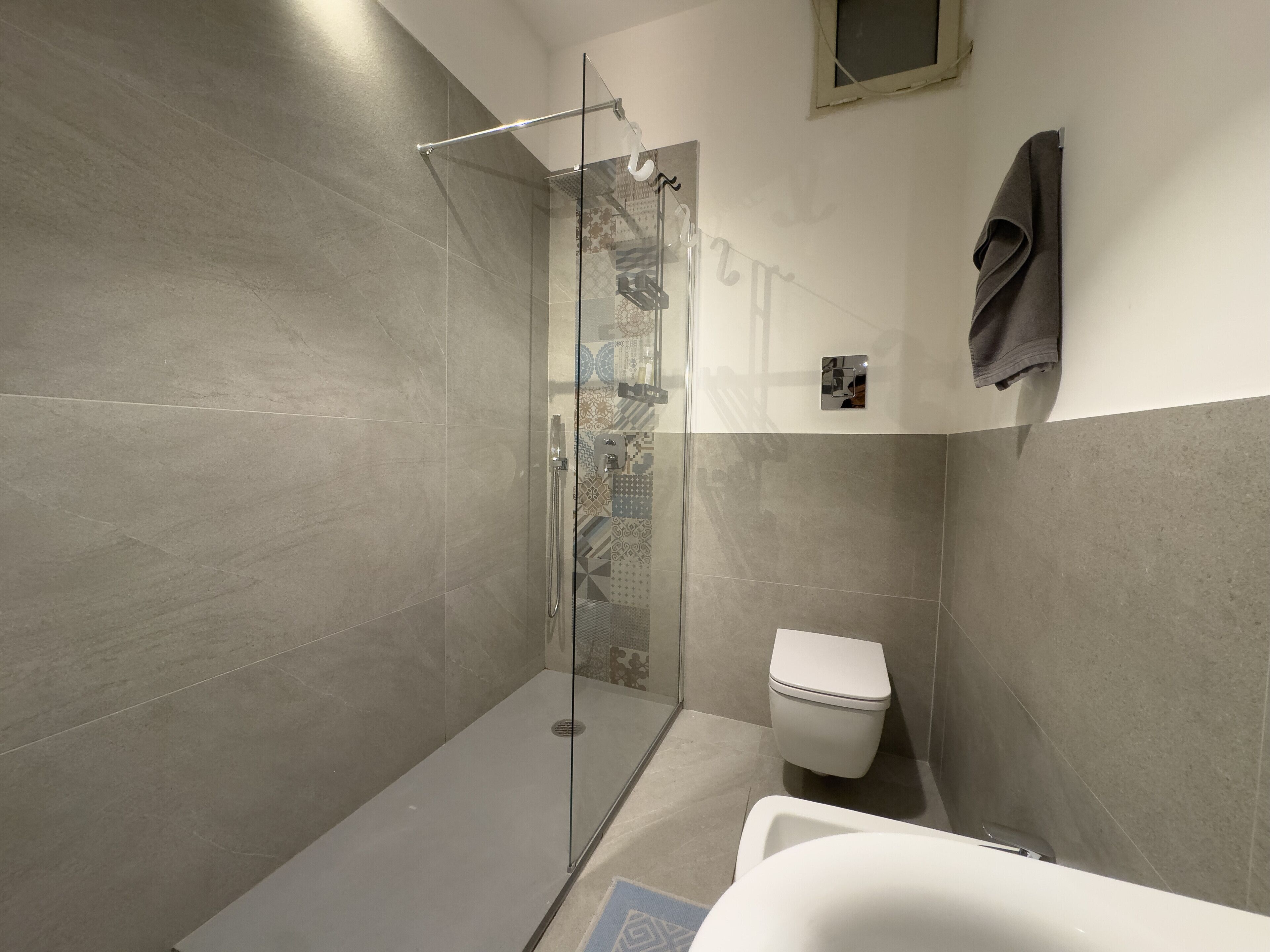 A modern bathroom with a glass shower enclosure, a white toilet, and a bathtub.