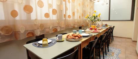 A dining area with a long table set for multiple people, featuring a variety of dishes and drinks.