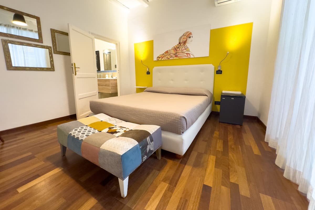 A bedroom with a bed, a bedside table, a mirror, and a wardrobe.