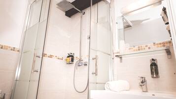 Une salle de bain moderne avec une douche à parois de verre, un lavabo blanc et un miroir au-dessus du meuble-lavabo.