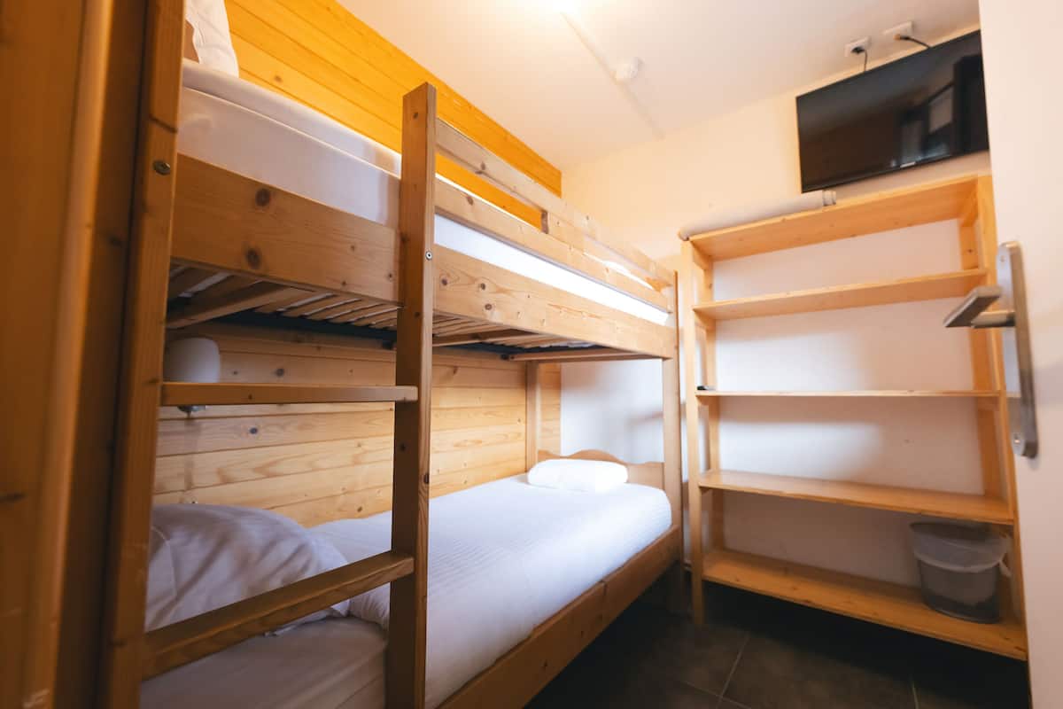 A bunk bed room with wooden walls and a TV mounted on the wall.