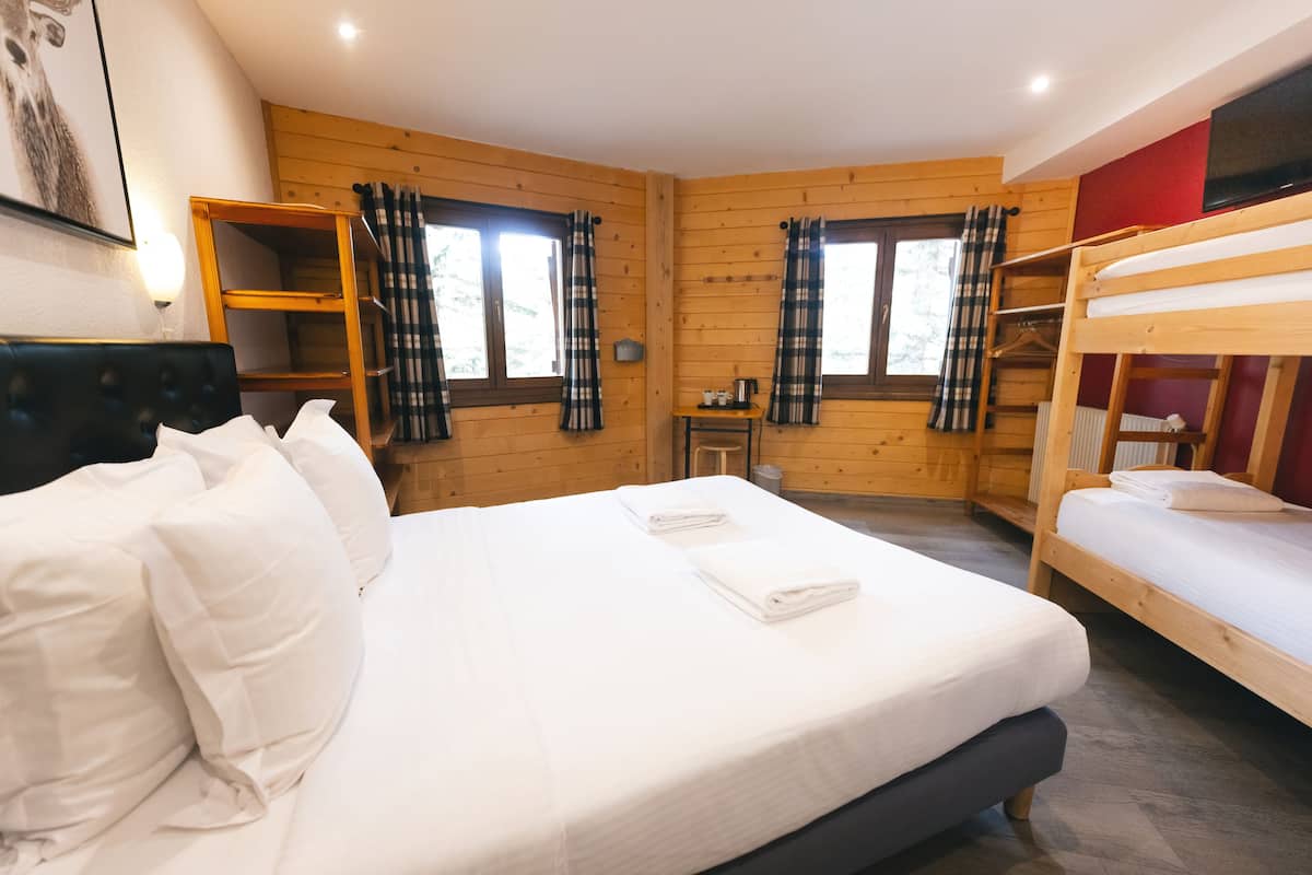 A room with a large bed, a smaller bed, a desk, and a TV.