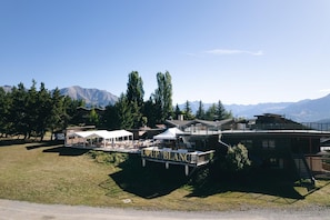 A hotel with outdoor seating, a deck, and a mountain backdrop.