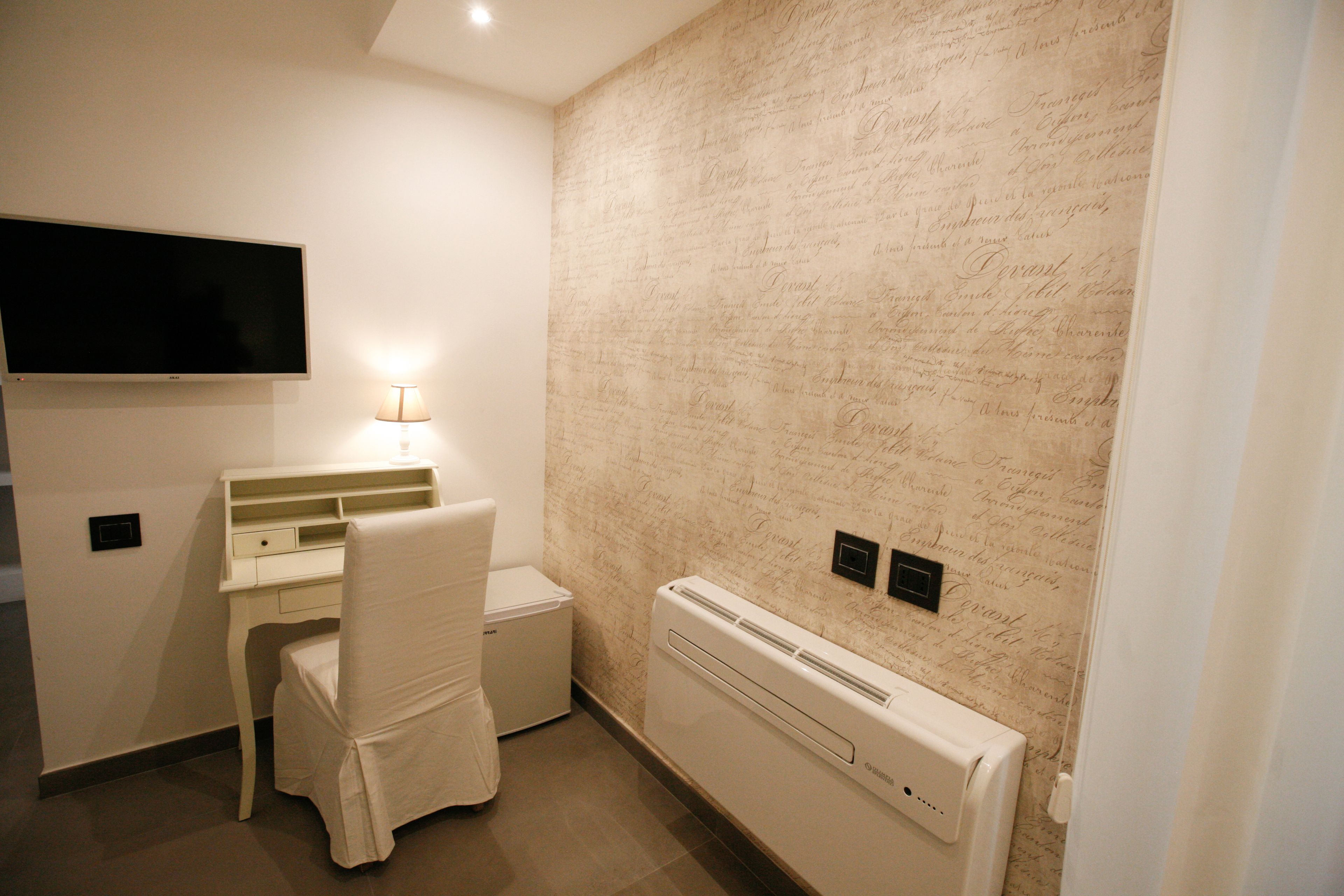 Una habitación pequeña y moderna con escritorio, silla y televisor de pantalla plana montado en la pared.