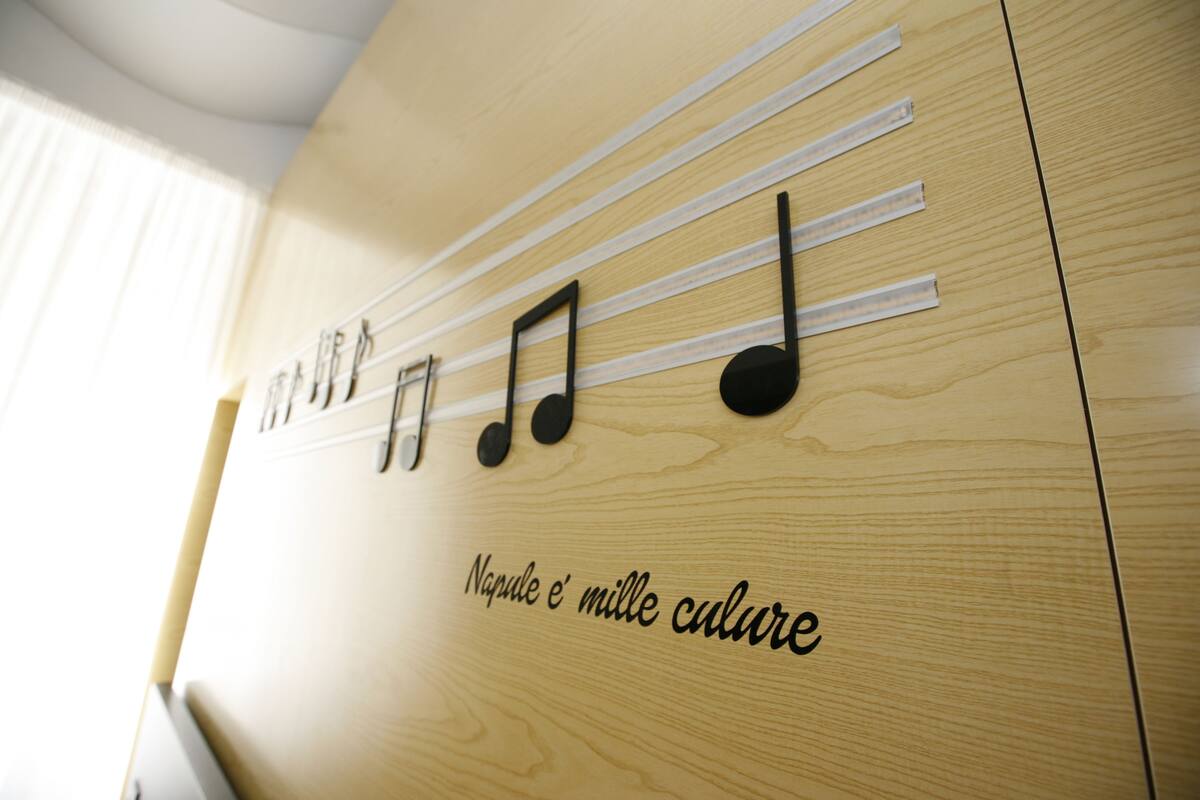 A wooden wall with musical notes and the text "Napule e' mille culture".