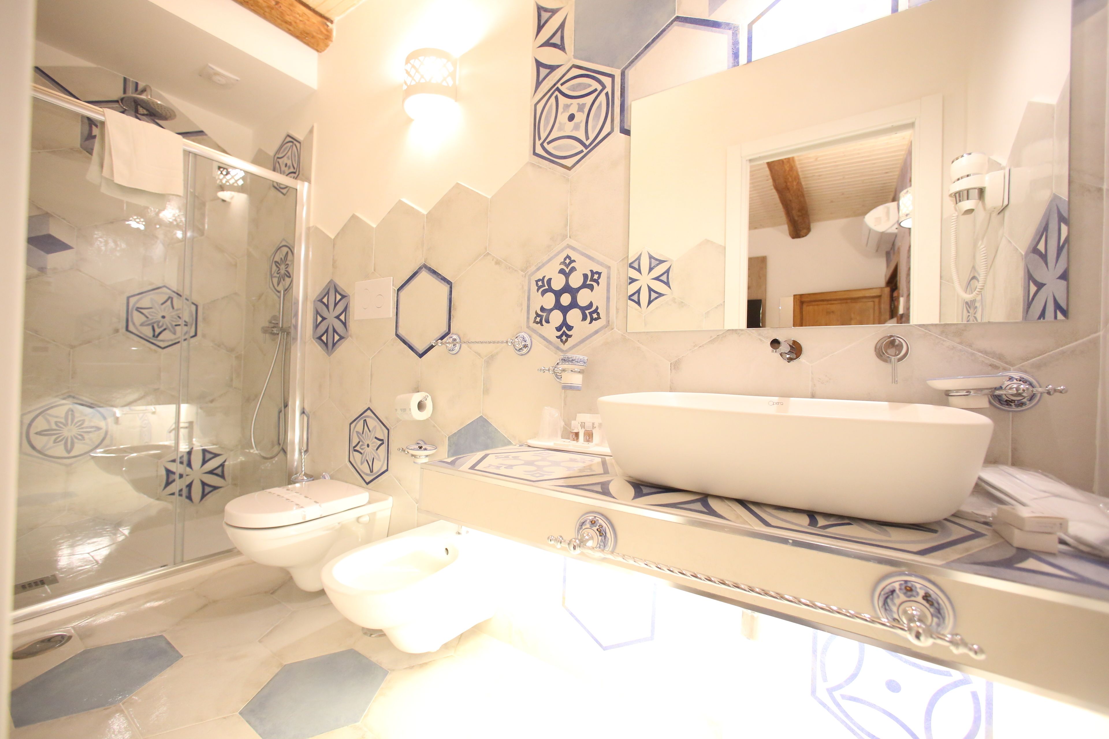 Un baño con ducha de mampara de vidrio, un lavamanos blanco y un espejo grande.