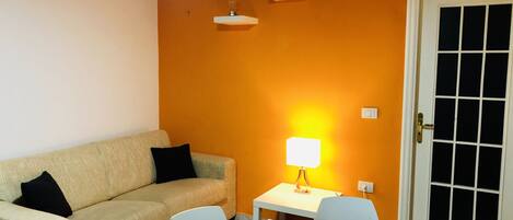 A living room with a beige sofa, a white table, and a lamp.