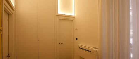 A hotel room with a large wardrobe, a radiator, and a window with curtains.