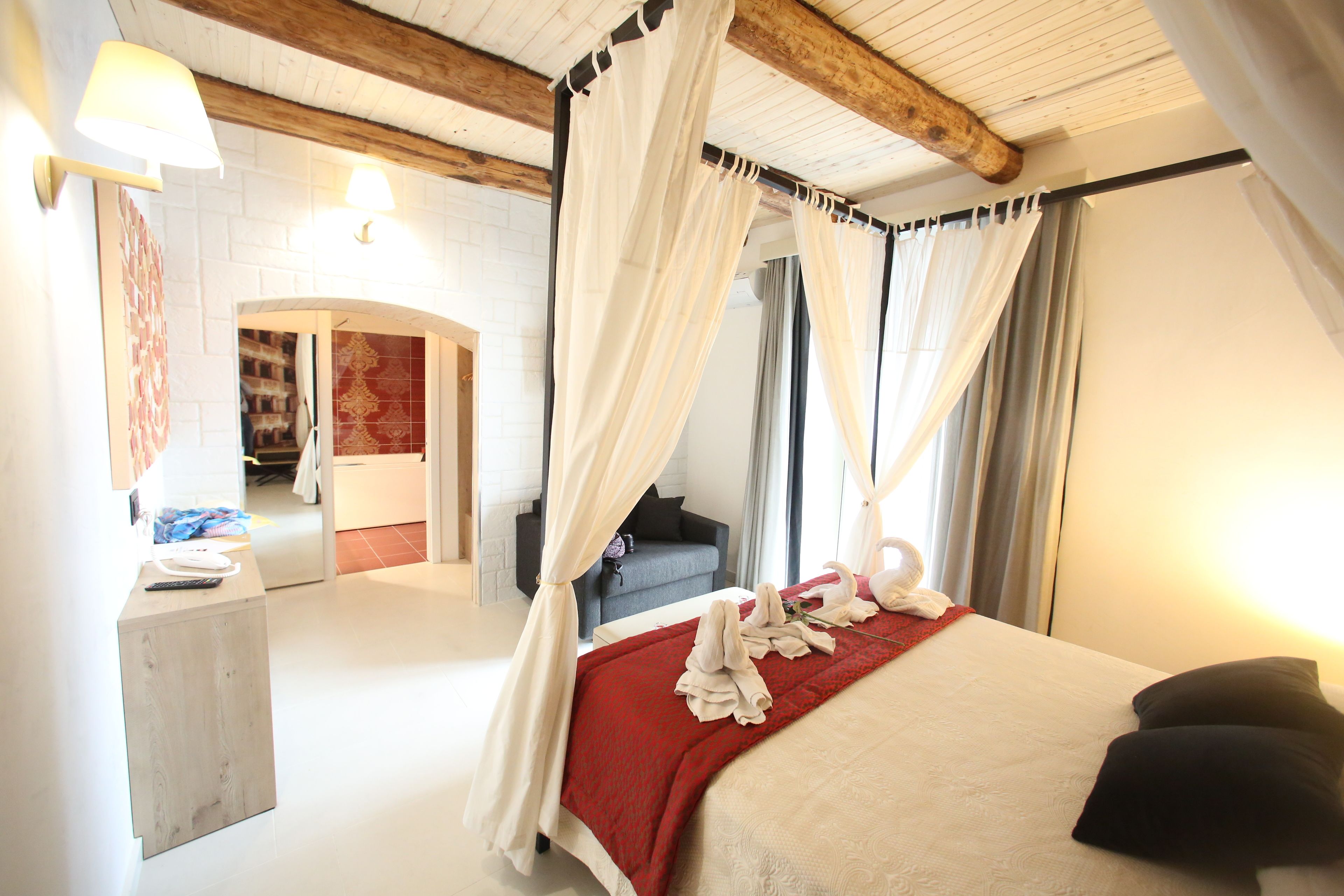 Un dormitorio con cama a dosel, una zona de estar con sofá y un pequeño escritorio.