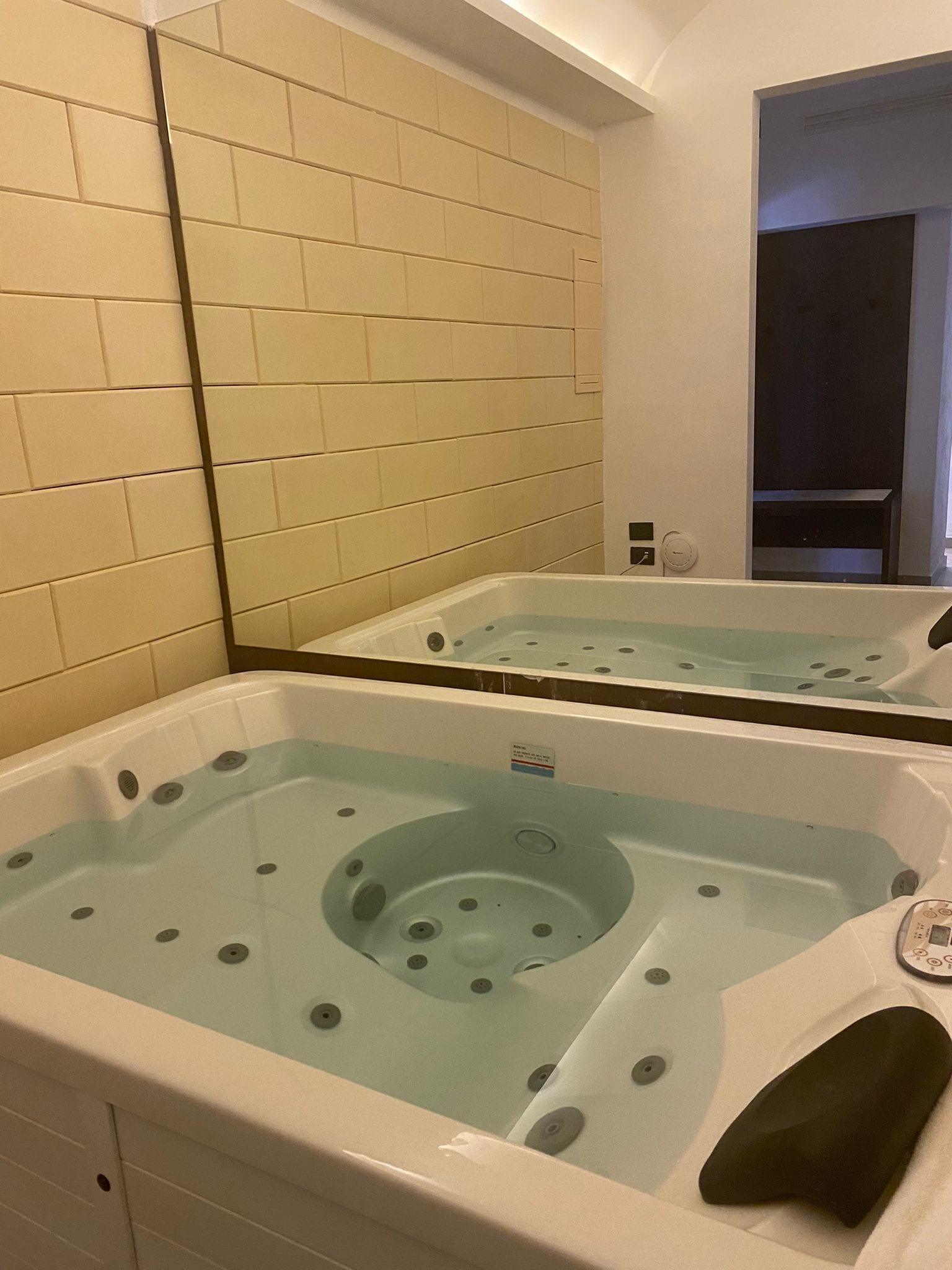 Ein Badezimmer mit einer großen Badewanne, einem Spiegel und einer gefliesten Wand.
