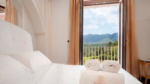 Habitació d'hotel amb un llit, vista a les muntanyes i un balcó amb barana.