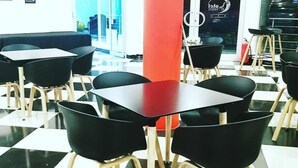 A restaurant with black and white checkered flooring, black chairs with wooden legs, and a red pillar. - Hotel Al-Khalil (Matola)