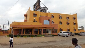 A multi-story hotel with a yellow facade, multiple air conditioning units, and a large sign indicating it is a luxury hotel. - Hotel Al-Khalil (Matola)