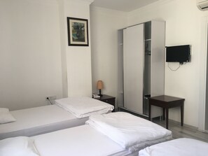 A hotel room with two single beds, a wardrobe, a desk, a lamp, and a TV mounted on the wall. - Mutado Hotel (Antalya)