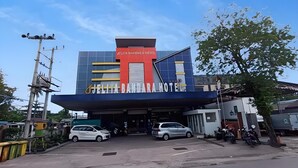 Un hôtel doté d’une façade moderne, d ’une entrée couverte et d’un parking où sont stationnées des voitures et des motos.