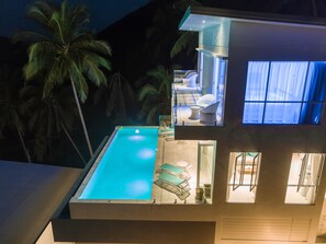 A modern house with a swimming pool, a balcony with outdoor furniture, and a view of palm trees. - Villa Melo (Koh Samui)