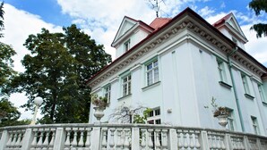 A white building with a red roof, a balcony with balustrades, and potted plants. - Hotel Villa Ostrava (Ostrava)
