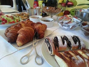 A table with pastries, including croissants and a cake with black and white stripes, and various condiments and fruits. - Hotel Villa Ostrava (Ostrava)
