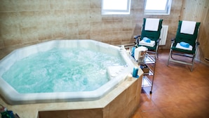 A bathroom with a large bathtub, two green chairs, and a bottle of shampoo. - Hotel Villa Ostrava (Ostrava)