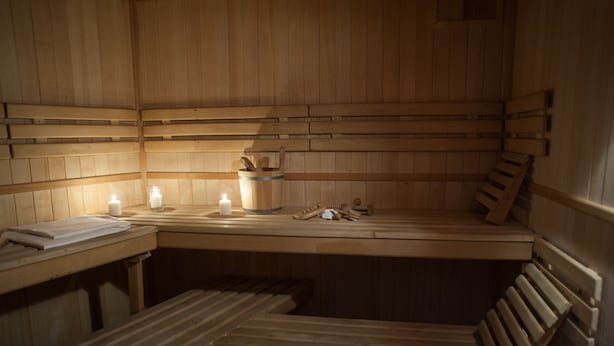 A wooden sauna with benches and a table, equipped with candles and wooden tools. - Hotel Villa Ostrava (Ostrava)
