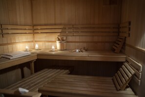 A wooden sauna with benches and a table, equipped with candles and wooden tools. - Hotel Villa Ostrava (Ostrava)