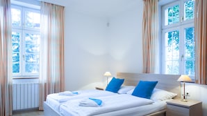 A hotel room with a large bed, two bedside tables, and a window with curtains. - Hotel Villa Ostrava (Ostrava)