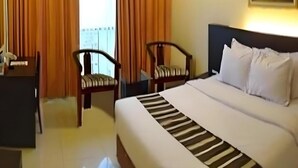 Habitación de hotel con cama, dos sillas, un escritorio y un cuadro en la pared.