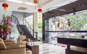 A hotel lobby with a staircase, seating area, and a large window with a view of the street.