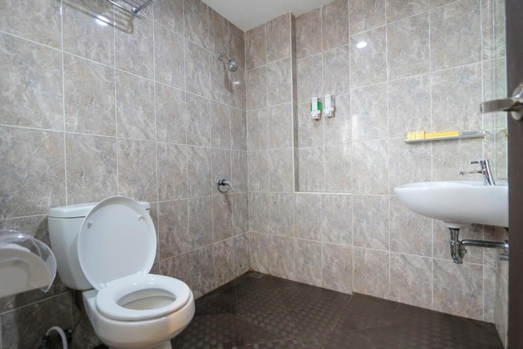 A bathroom with a toilet, a shower, and a sink.
