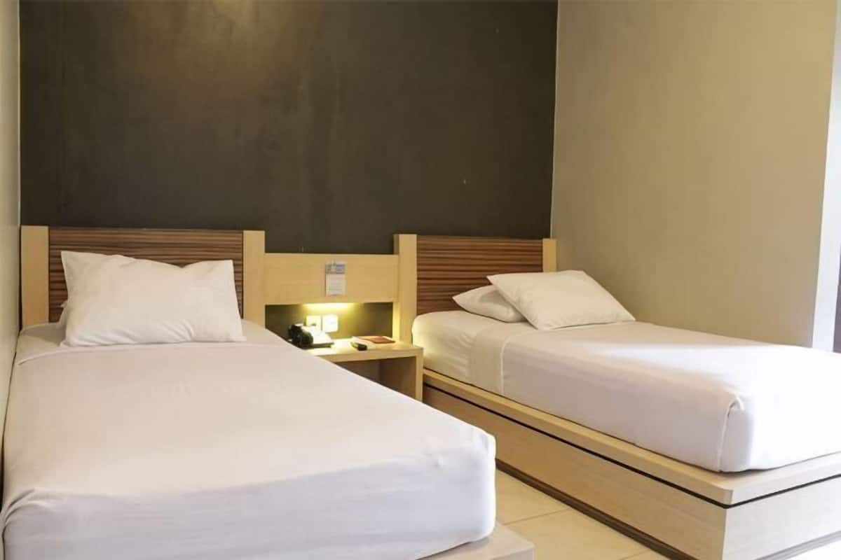 Two single beds with wooden headboards, bedside tables, and a nightstand with a lamp.