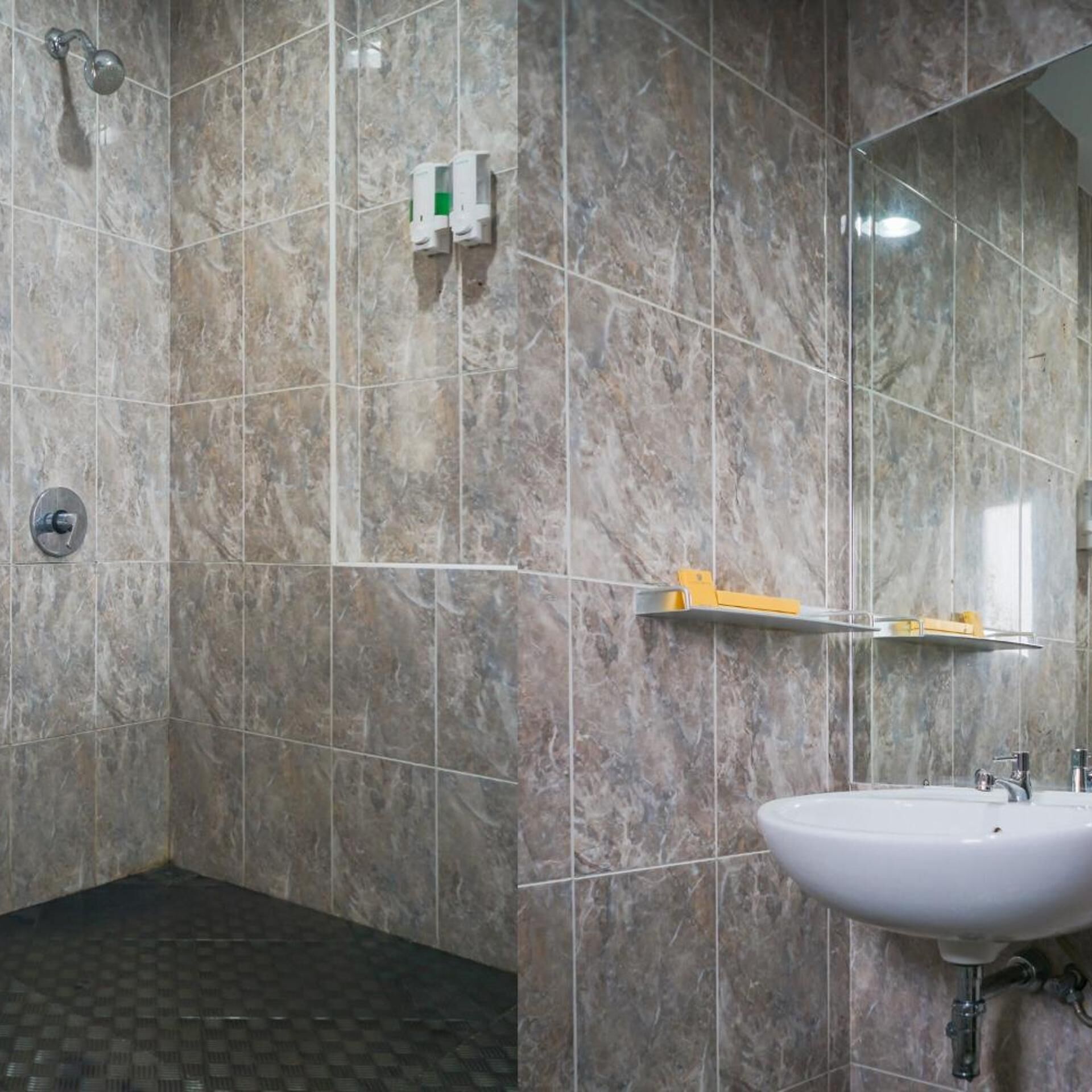 Un baño con ducha, lavabo y espejo.