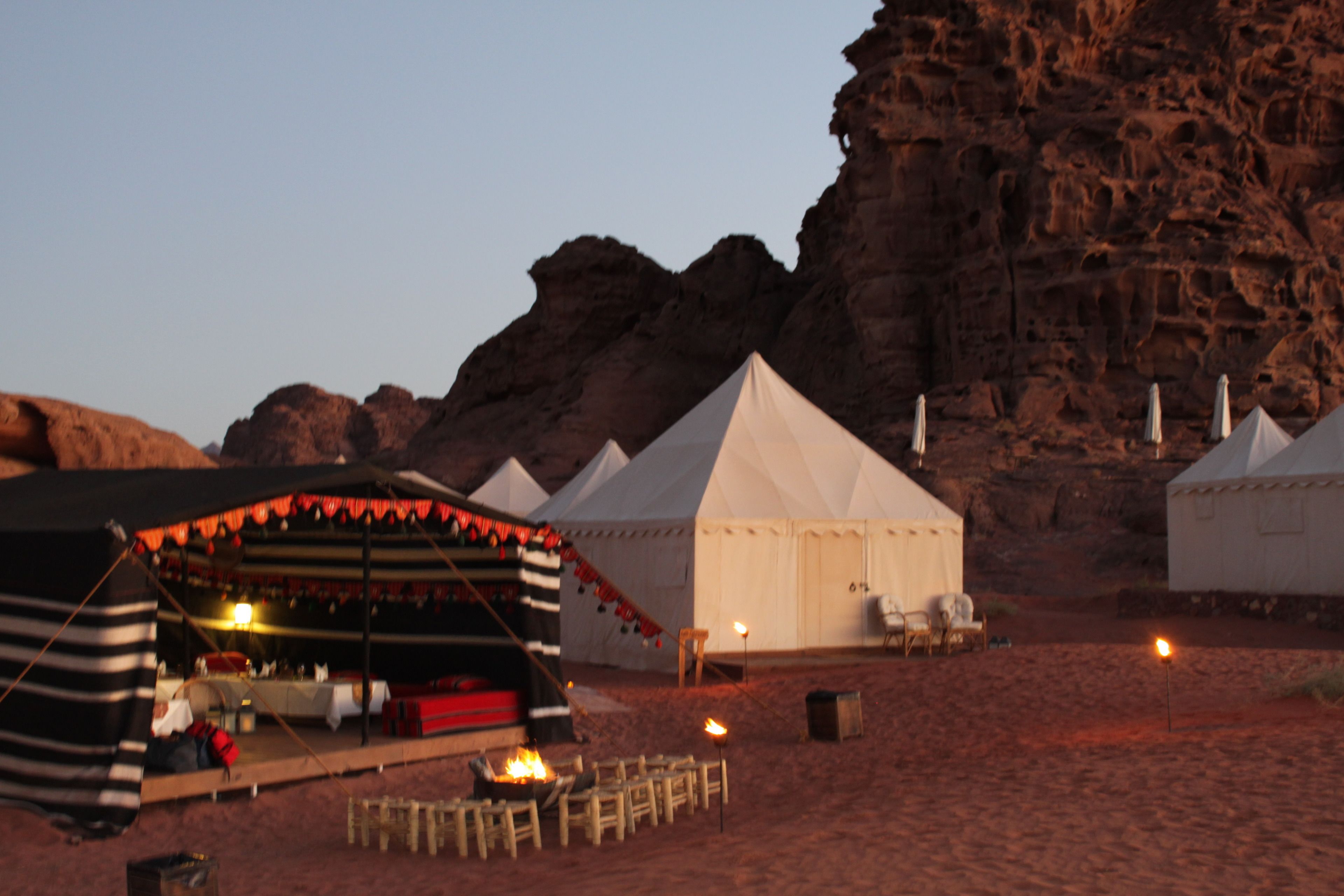 A desert campsite with tents and a dining area with tables and chairs.
