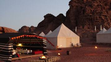 A desert campsite with tents and a dining area with tables and chairs.