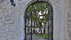 An entrance to the Heaven Cave House with a wrought iron gate, stone walls, and outdoor seating area. - Heaven Cave House (Ürgüp)