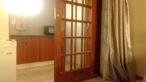 A kitchen with wooden cabinets, a refrigerator, and a tiled floor. - Comfort Palace Guest House Francistown (Francistown)