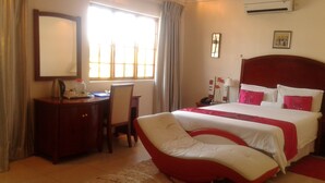 A hotel room with a large bed, a desk, a chair, and a window with curtains. - Comfort Palace Guest House Francistown (Francistown)