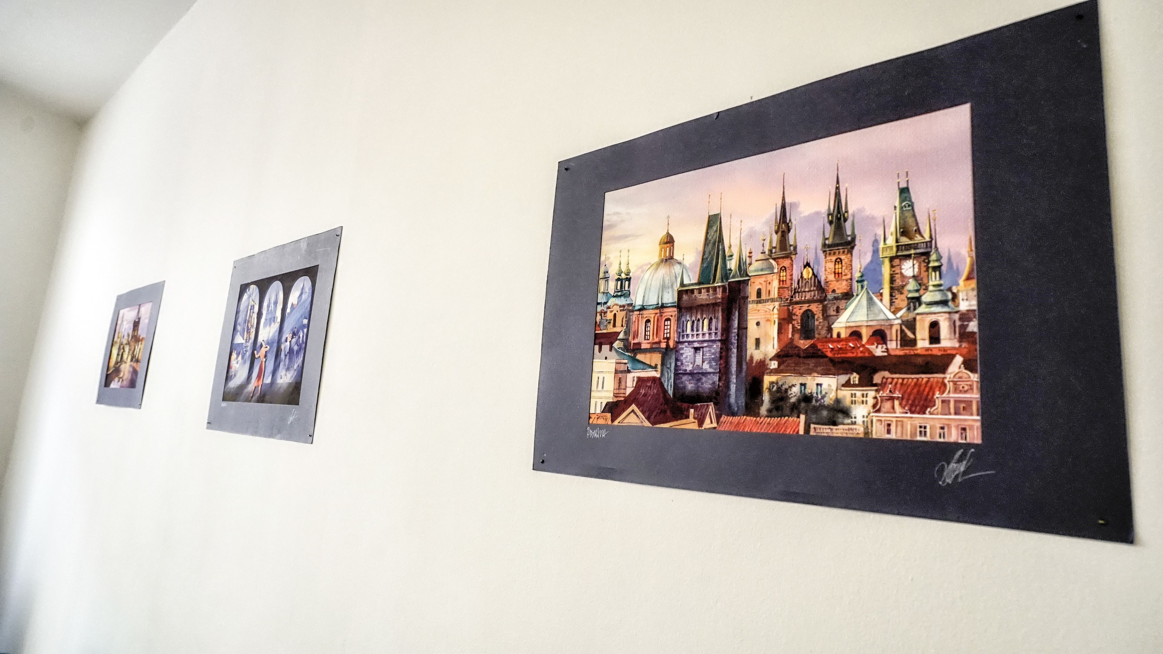 Drie kunstwerken in lijsten aan een muur.