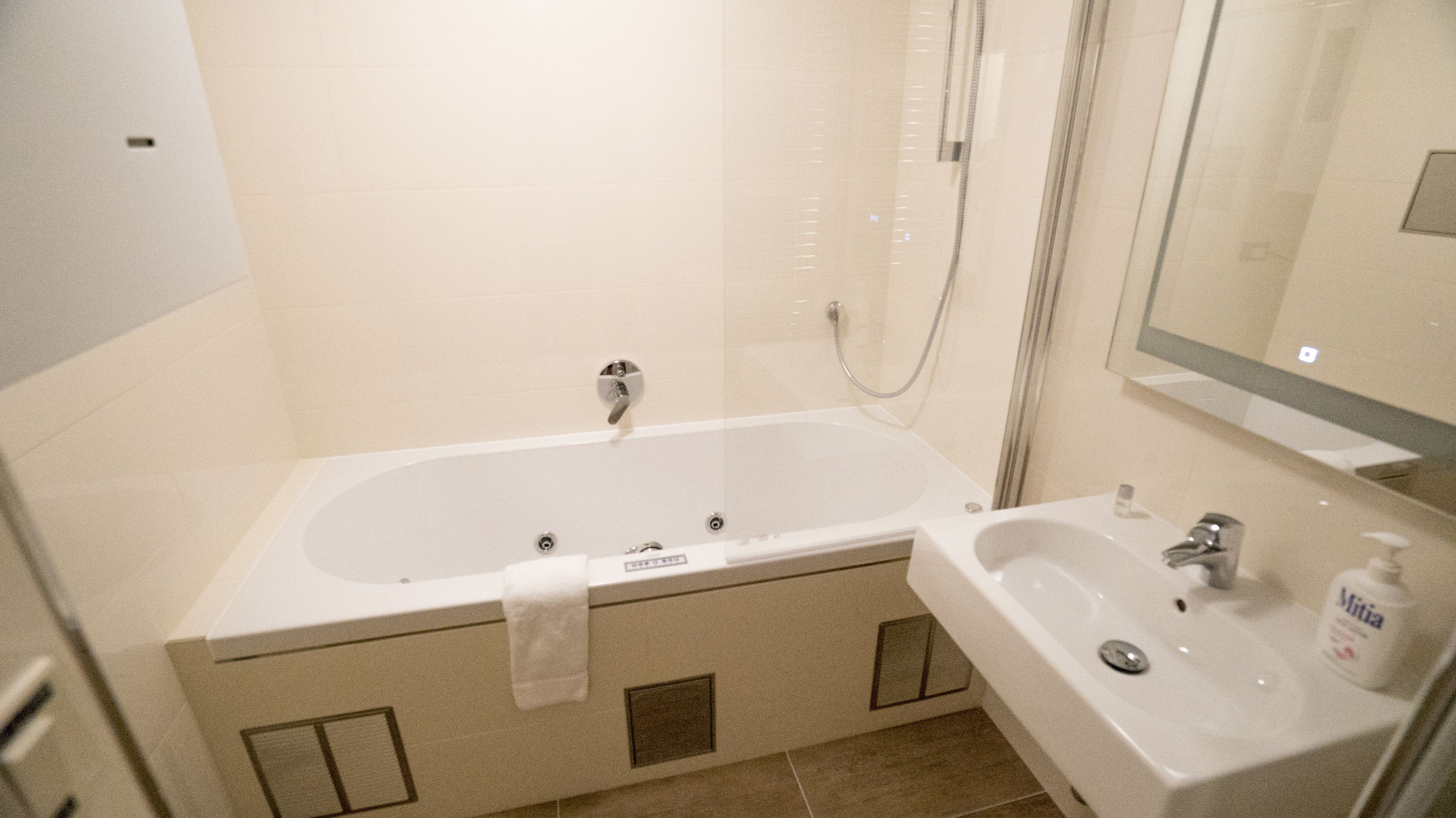 A bathroom with a bathtub, a sink, and a mirror.