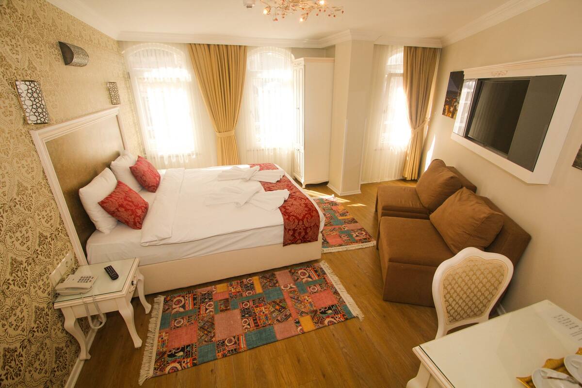 Een hotelkamer met een bed, een bank, een klein tafeltje en een televisie.