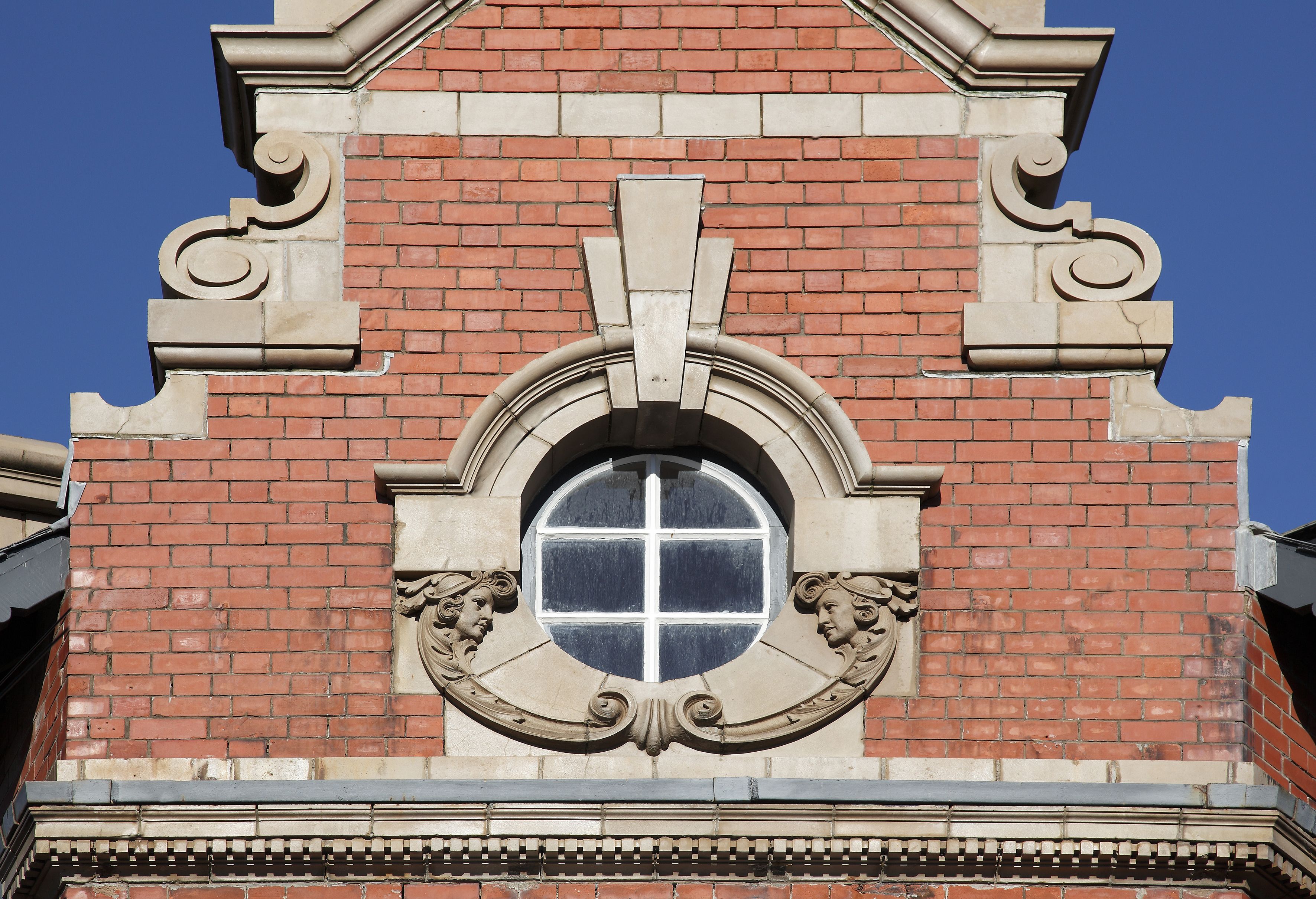 A brick building with a large arched window and decorative stone carvings.