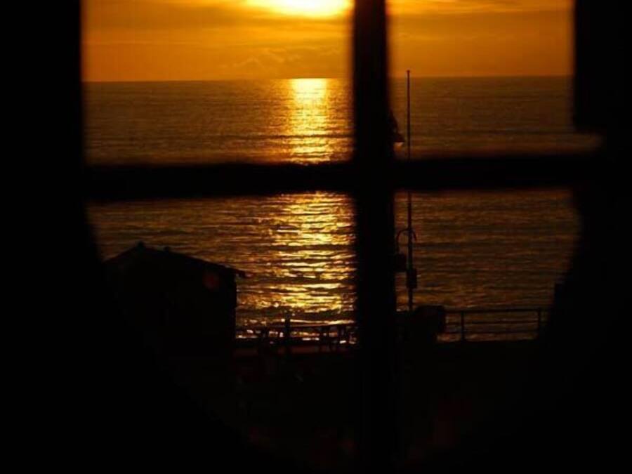 A sunset view through a window with a view of the ocean.