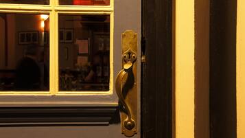 Une porte dotée d’une poignée en laiton et une fenêtre donnant sur une pièce à l’intérieur.